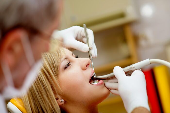 Dentist working on a woman's teeth, a silent luxury for rich people that normal people might not consider.