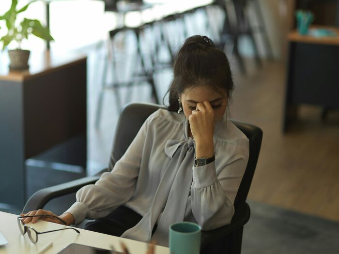 Stressed woman sitting at desk with headache in office environment