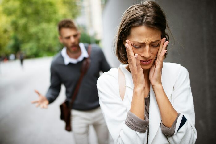 Upset woman with hands on face as man argues nearby illustrating cult escape moment