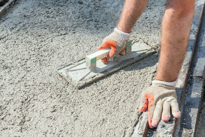 Worker smoothing wet concrete displaying interesting construction facts