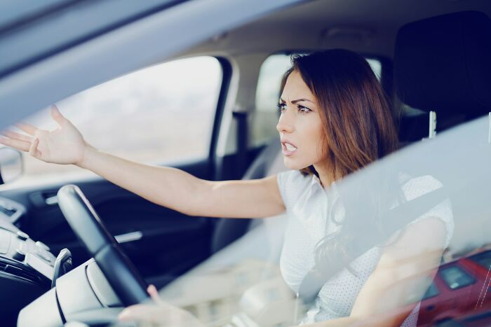Angry woman gesturing while driving a car on the road
