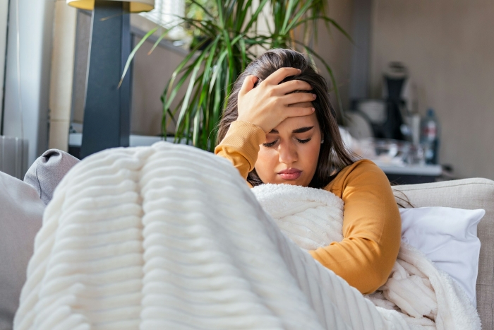 A woman with a headache under a blanket, looking distressed. She made a mistake and needs to defend herself.