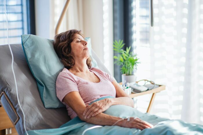 A woman with an IV in a hospital bed, eyes closed, resting. This image depicts a disturbing d***h story.