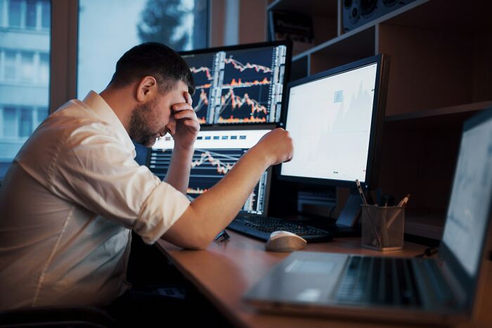 Stressed man monitoring stock market on multiple screens