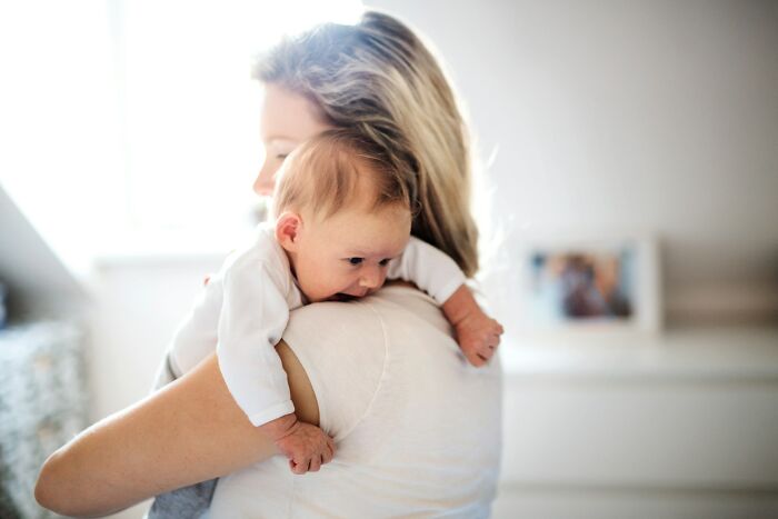 A mother holding a newborn baby over her shoulder, softly lit, representing pure love, a monster client's lawyer's opposite.