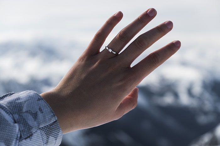 Hand with an engagement ring against a blurred mountain background Hand with an engagement ring against a blurred mountain background
