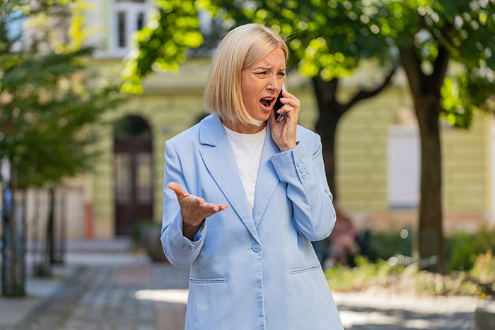Woman in blue blazer angrily talking on phone outdoors Woman in blue blazer angrily talking on phone outdoors