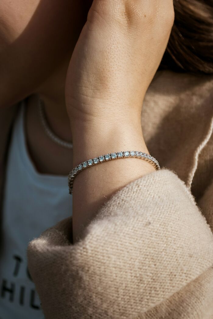 Close-up of a wrist wearing a sparkly bracelet, with a beige sweater sleeve. Question reality, glitches in the matrix.
