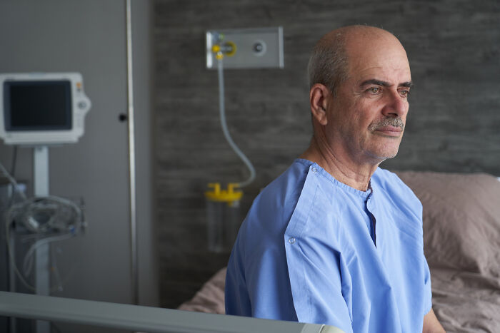 Patient sitting in hospital room wearing hospital gown