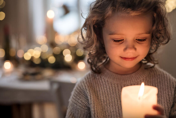 Child holding lit candle causing potential fire hazard