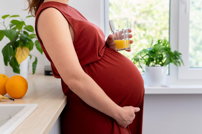 Pregnant woman holding glass of juice at home