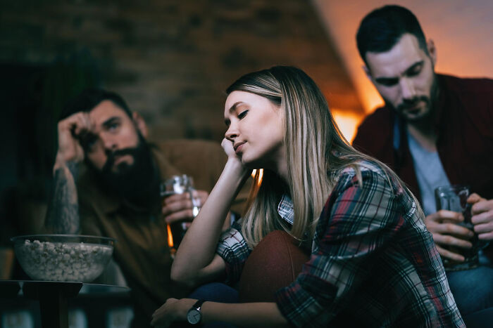 Bored young woman with friends watching TV