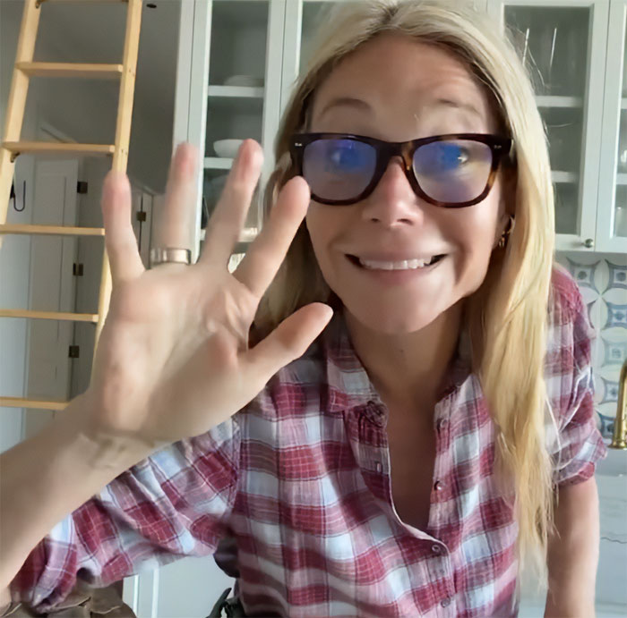 Gwyneth Paltrow smiling and waving in kitchen wearing plaid shirt Gwyneth Paltrow smiling and waving in kitchen wearing plaid shirt