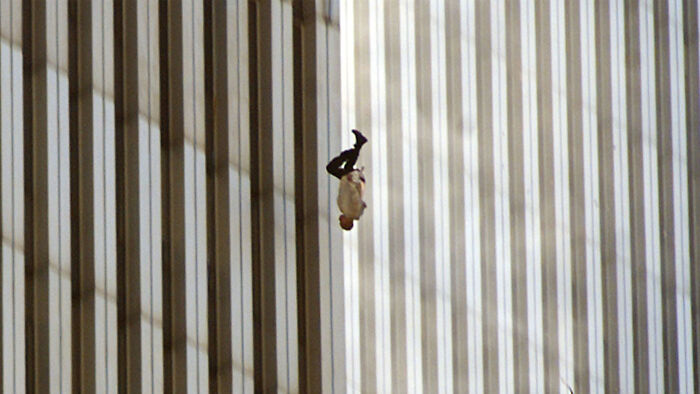 Person captured mid-fall from tall building with vertical window stripes in background