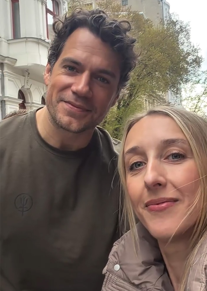 Henry Cavill smiling with a woman outdoors showing new look with men expiration date theme