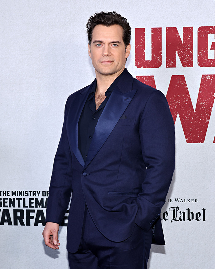 Henry Cavill posing in a navy blue suit at a red carpet event for men expiration date look