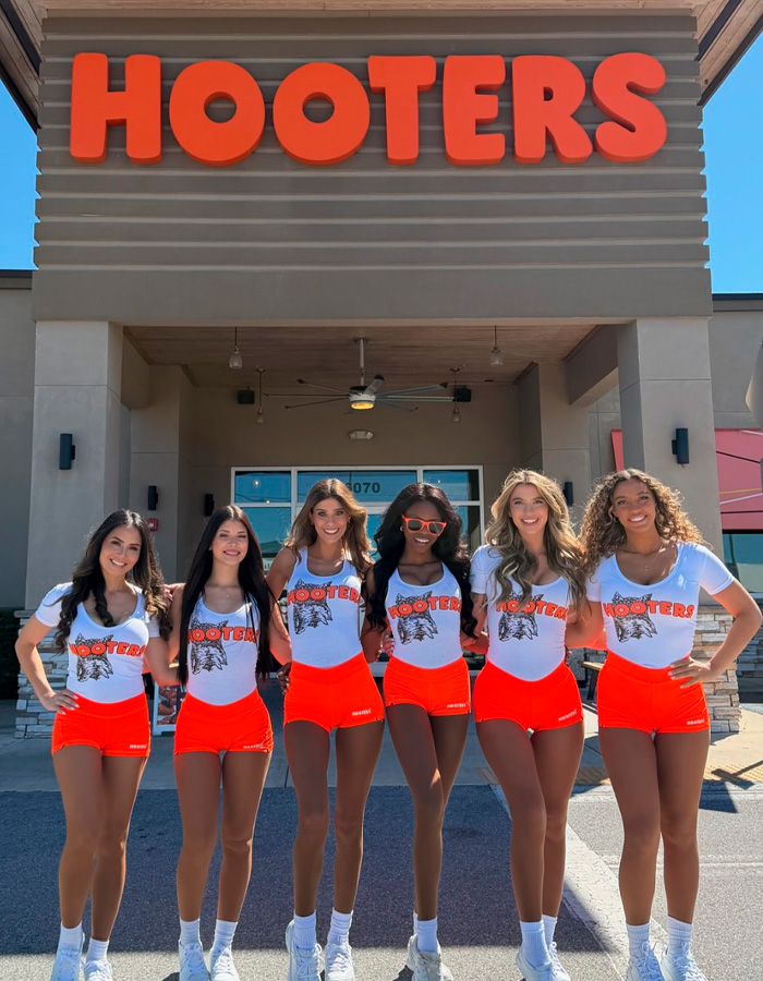 Group of Hooters waitresses posing outside restaurant entrance Group of Hooters waitresses posing outside restaurant entrance
