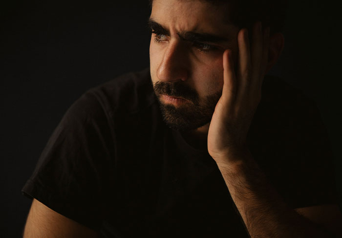 Worried man tenant resting hand on face in dark room