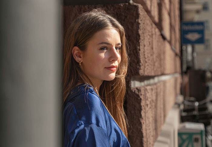 Young woman tenant leaning against brick wall in urban rental setting