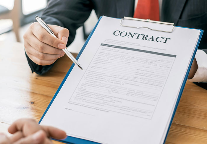 Person holding contract with pen, representing lease agreements and tenant obligations