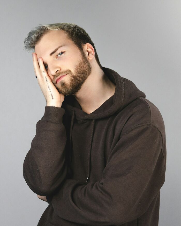 Young man with beard touching face and looking pensive