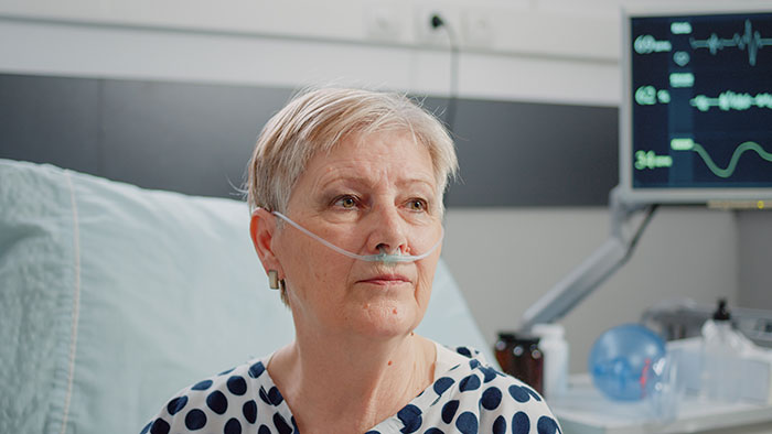 Woman with oxygen nasal cannula in hospital bed battling cancer Woman with oxygen nasal cannula in hospital bed battling cancer