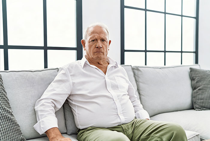 Sad elderly man sitting on couch during difficult cancer battle Sad elderly man sitting on couch during difficult cancer battle