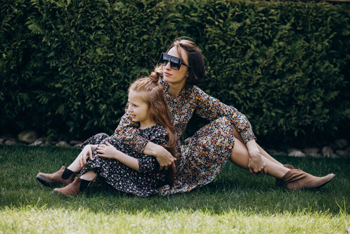 Woman and daughter sitting on grass in a garden, highlighting family life