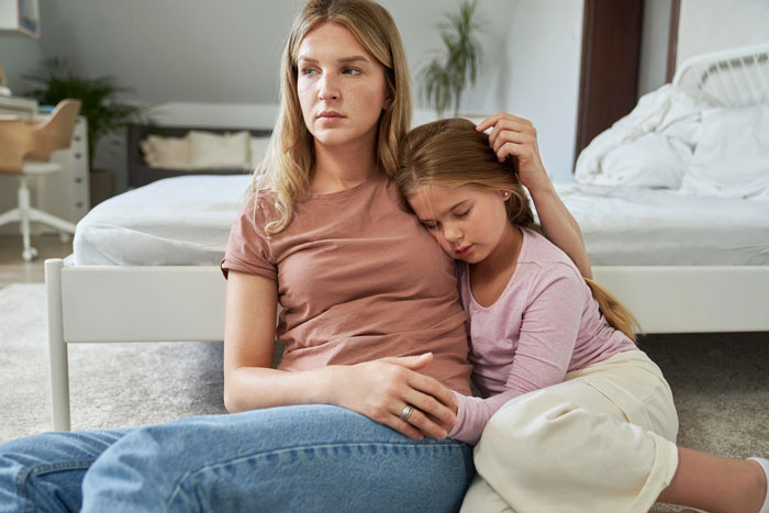 Worried mother consoles daughter in bedroom, reflecting emotional impact of cheating husband's actions