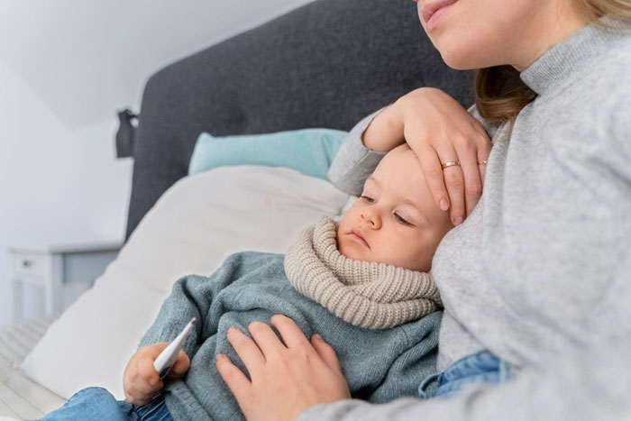 Mother holding sick child with fever resting in bed during bachelor trip Mother holding sick child with fever resting in bed during bachelor trip