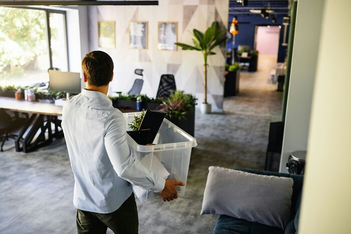 Man carrying a clear box of personal items, leaving an office, illustrating instant privilege.