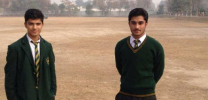 Two boys in school uniforms on field in creepy photo