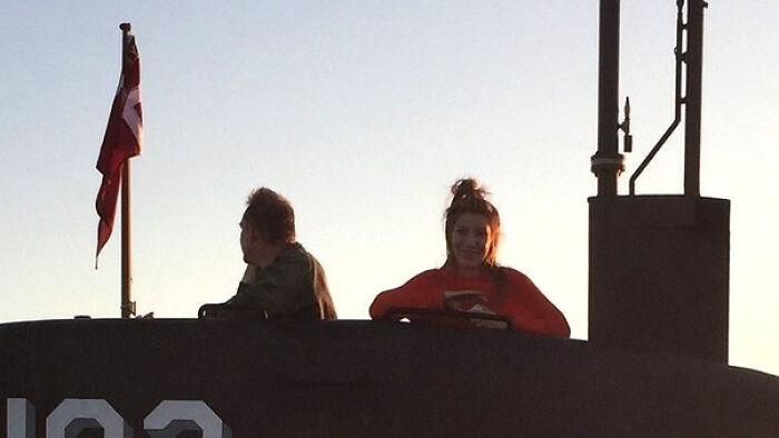Creepy photo of two people on a submarine with a flag at sunset