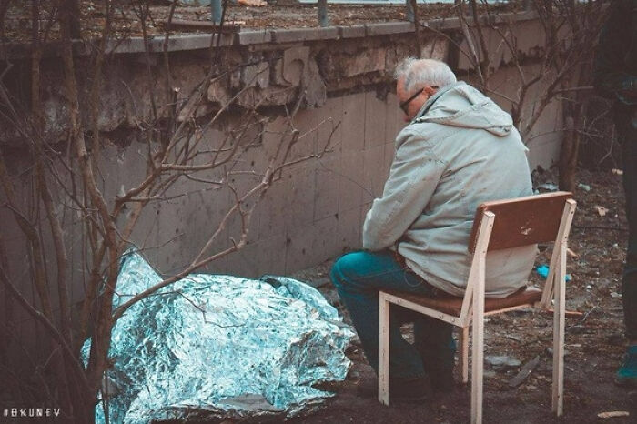 Sad man sitting on a chair near a mysterious shiny silver bundle outdoors