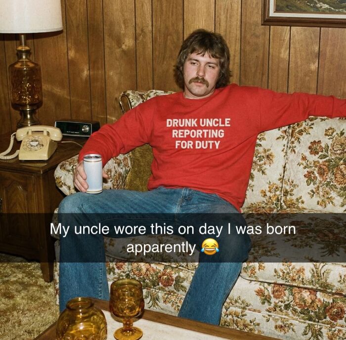 A man wearing a red sweatshirt with the text DRUNK UNCLE REPORTING FOR DUTY, a bizarre and unhinged t-shirt.