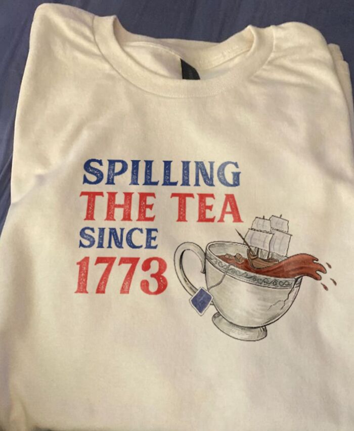 A white T-shirt with the text Spilling the Tea Since 1773, with an image of a ship spilling out of a teacup, a brilliant T-shirt.