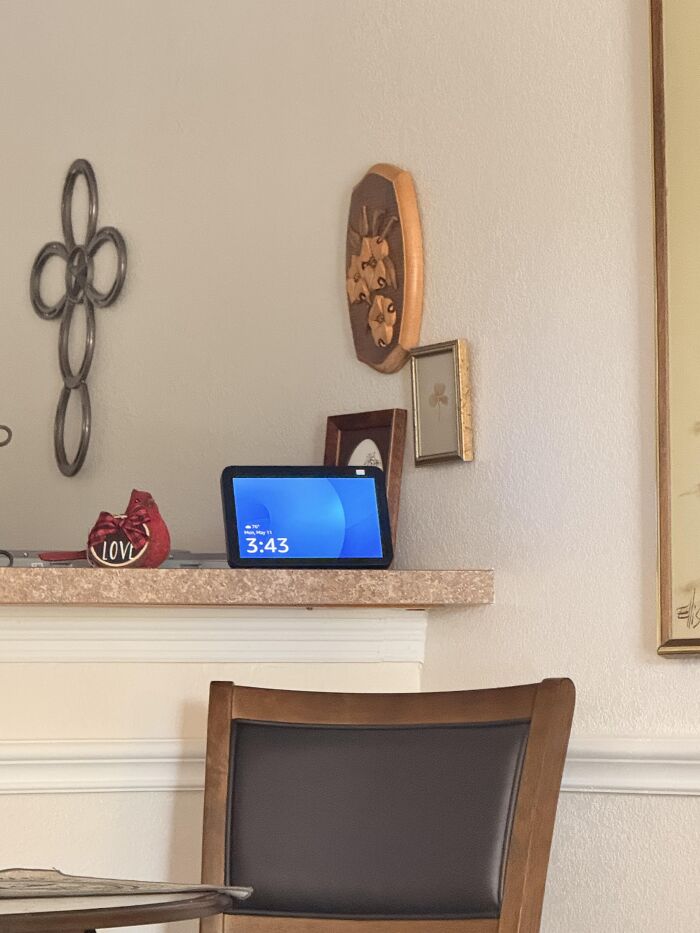 A smart scale on a shelf showing 3:43, with a Love decoration and wall art, highlighting technology and relationships.