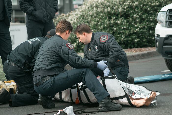 First responders carefully attend to a person wrapped in a thermal blanket, suggesting a very creepy situation or emergency.