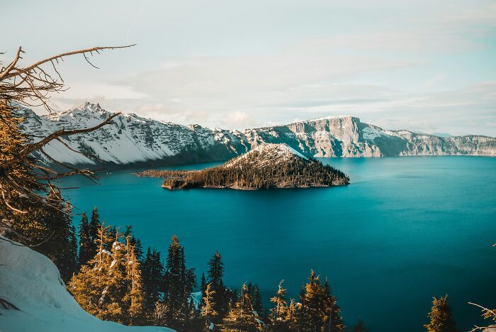 Crystal blue lake surrounded by snowy mountains and forest landscape geography facts