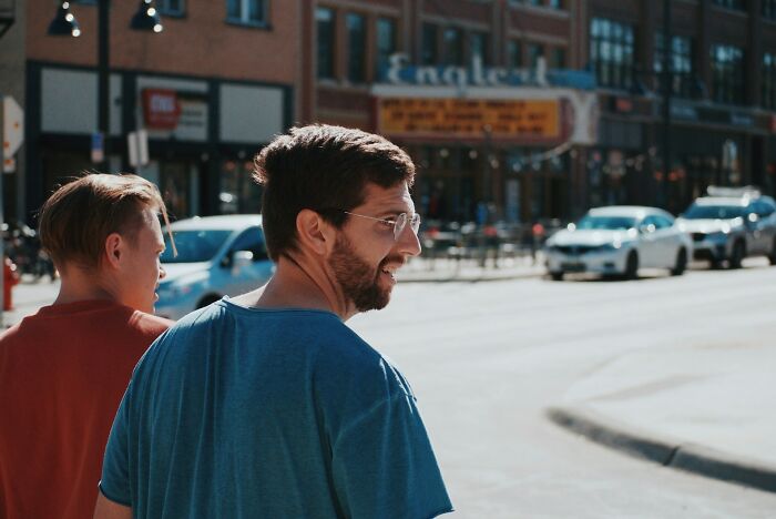 Man smiling and standing near cars on busy city street
