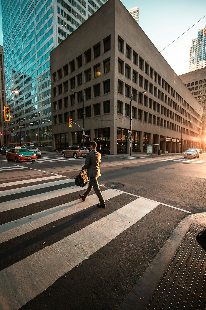 Man walking across city crosswalk at sunset in urban area