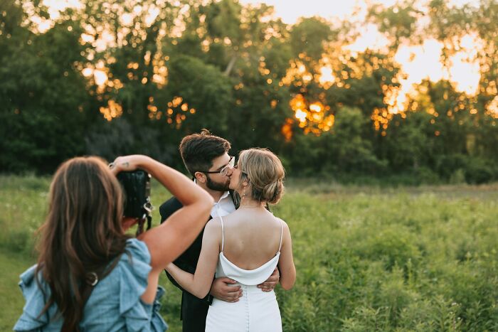 Photographer capturing bride and groom kissing at outdoor wedding wedding photography