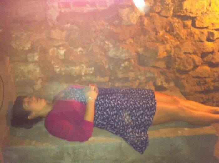 Woman lying still on a stone bench in a dimly lit room mysterious bench photo
