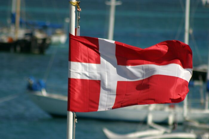 Danish flag waving in front of boats representing Denmark economics