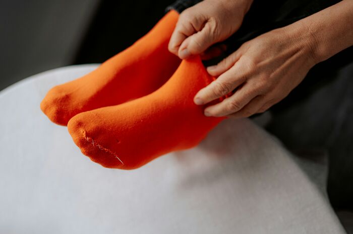Close-up of hands adjusting bright orange socks, illustrating small moments in long term partners