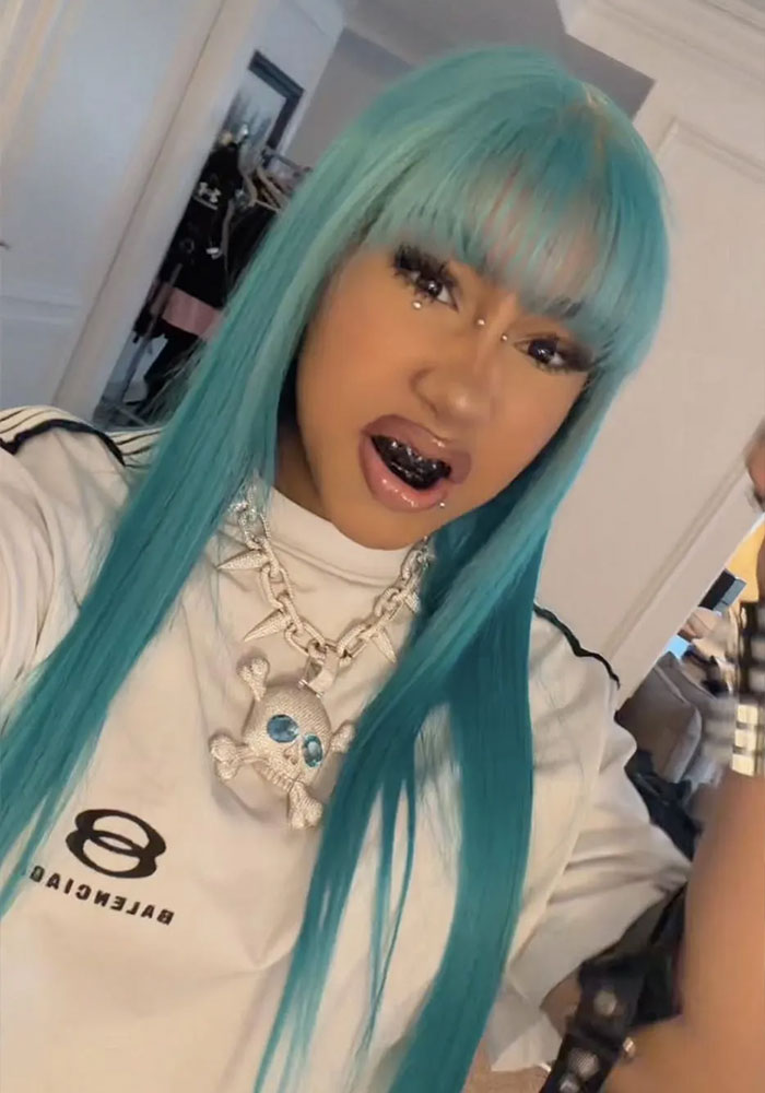 Woman with long teal hair and bold jewelry wearing white Balenciaga top and black grill Woman with long teal hair and bold jewelry wearing white Balenciaga top and black grill