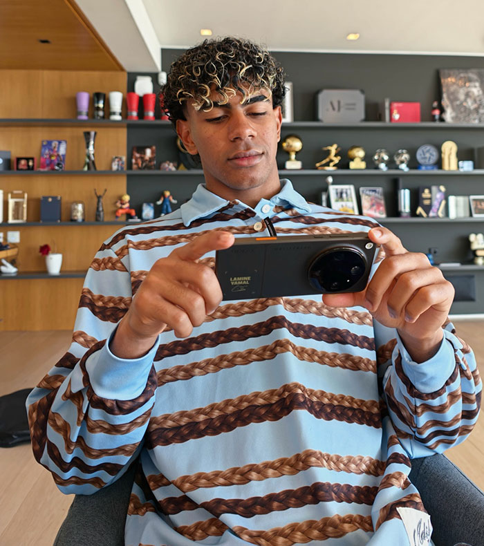 Pro athlete wearing casual striped shirt holding a phone indoors Pro athlete wearing casual striped shirt holding a phone indoors