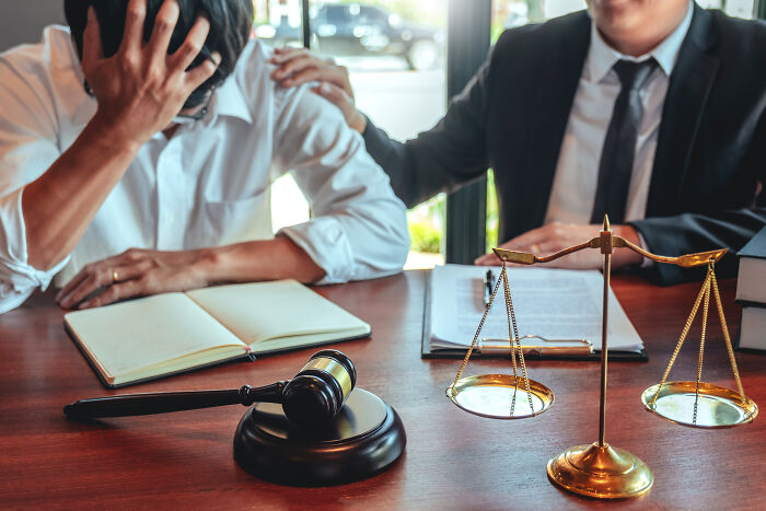 A distressed person being comforted by a lawyer during a legal consultation, showcasing hard cases lawyers face.