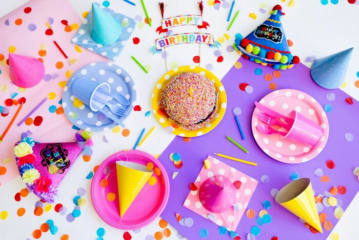 Colorful birthday party setup with a sprinkle cake, confetti, hats, and plates. Celebrating a milestone like 17 years.