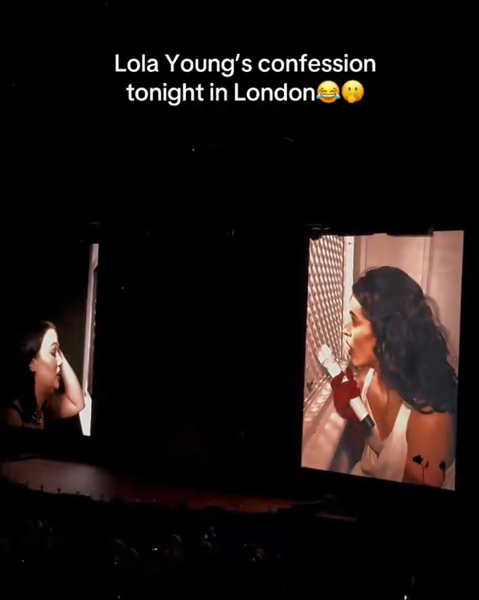 Lola Young on a large screen, performing live in London, caught out cheating lover.